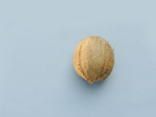 A closeup shot of a peeled coconut on the blue background