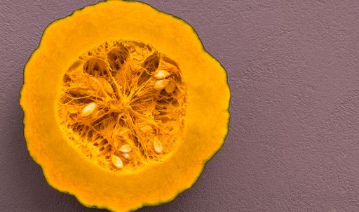 A top view shot of a sliced pumpkin on a purple surface