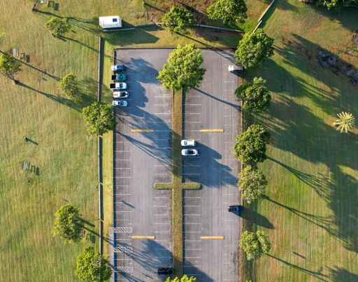 An aerial shot of a parking space surrounded by lush green fields