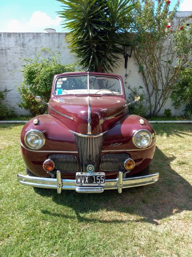 Old antique red 1941 Ford V8 Super Deluxe convertible club coupe Series 11A in a park. Front view. Chromes. Grille. CADEAA 2023 classic car show.