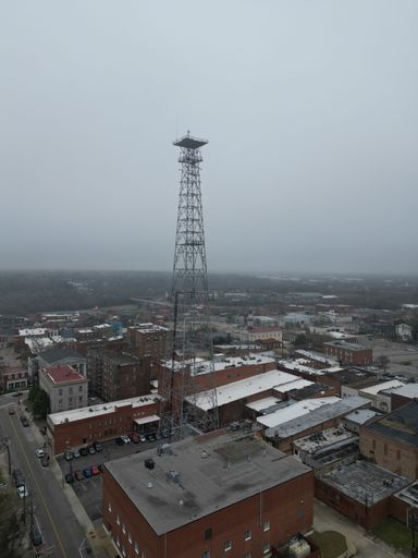 Vertical image of a city skyline featuring a tall, prominent tower with other buildings in the background