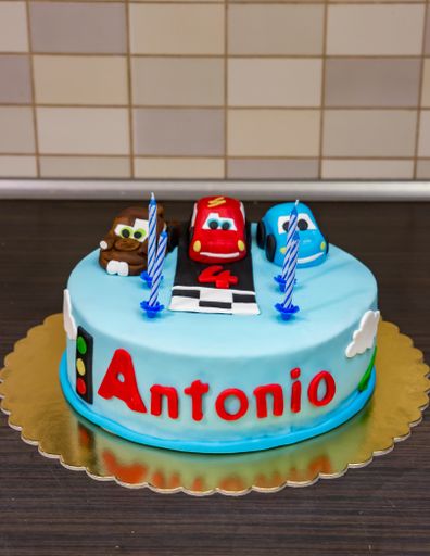 Cars birthday cake with number 4 and name Antonio on a table