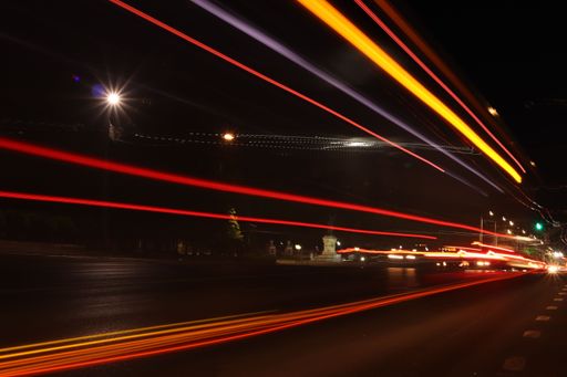 A long exposure shot of the light trails of transportation along the road in the city at night