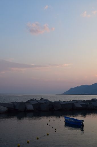 A vertical shot of a boat on the side of the calm and tranquil lake