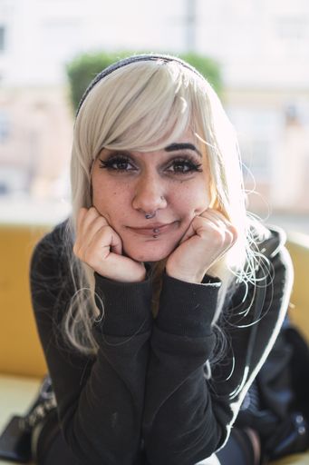 A cute young Spanish woman with blond hair and piercings resting her chin on her hands