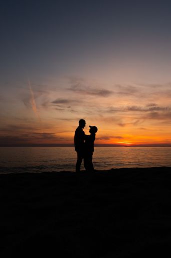 young couple posing backlit in a sunset on the beach in spring