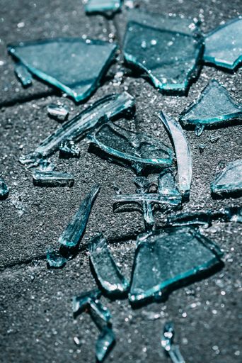 A vertical shot of broken glasses scattered on the concrete surface