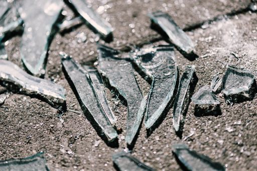 A closeup shot of broken glasses scattered on the concrete surface
