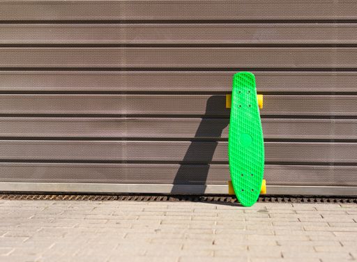 A green skateboard with yellow wheels resting on a door of a grey parking lot