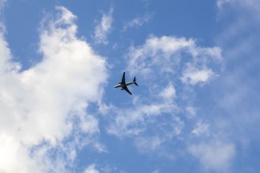 A low-angle shot of an airplane against the cloudy blue sky