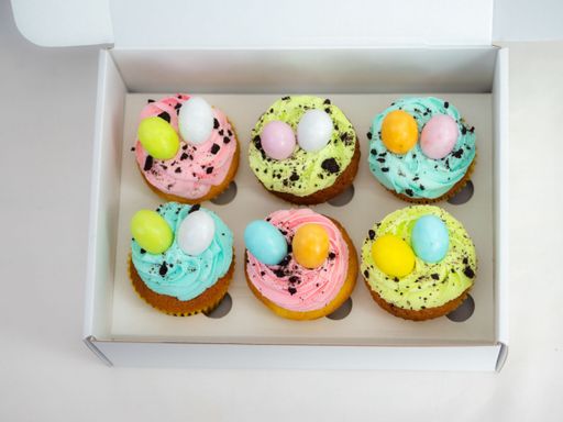 A box of colorful Easter cupcakes decorated with vibrant, brightly-colored eggs.