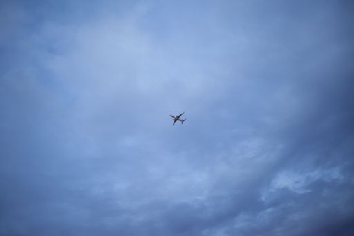 A low angle shot of a plane flying under a blue cloudy sky in the evening - great for wallpapers