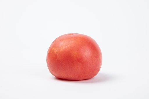 A closeup shot of a single tomato with water drops isolated on white background