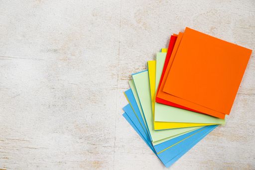 An overhead shot of a stack of colorful notepad on a white surface with space for your text