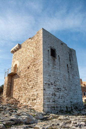 A vertical shot of an ancient castle with white bricks on the blue sky background