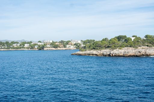 A beautiful seascape view of the blue seashore with a small town in the sky background