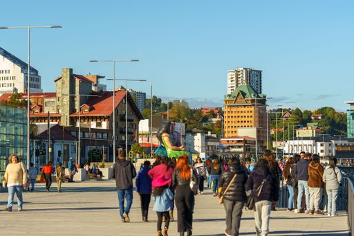 A group of people walking in the urban area with a grand clock tower in the background in Puerto Montt, Chile