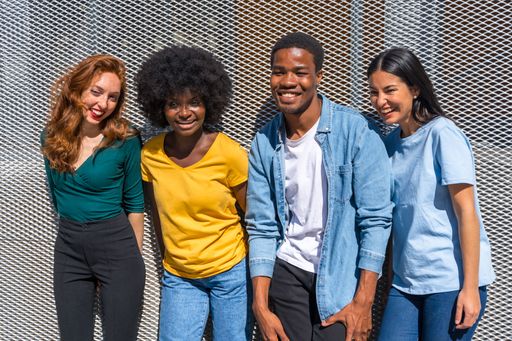 A cheerful group of diverse friends posing for a photo together against a gray wall