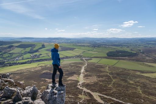 A high angle shot of a hiker enjoying the view from the Spink Glendalough Viewpoint in Ireland