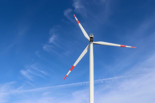 A low angle shot of a modern windmill under the sunlight and a blue sky in the countryside