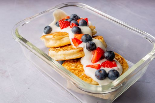 A closeup of delicious pancakes with fresh blueberries and raspberries on the transparent plate