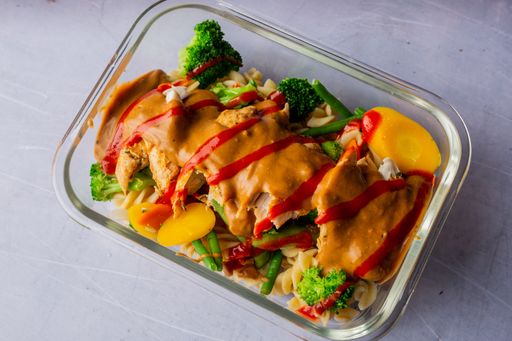 A closeup of a  plate with a variety of fresh ingredients, including chicken, broccoli, and other