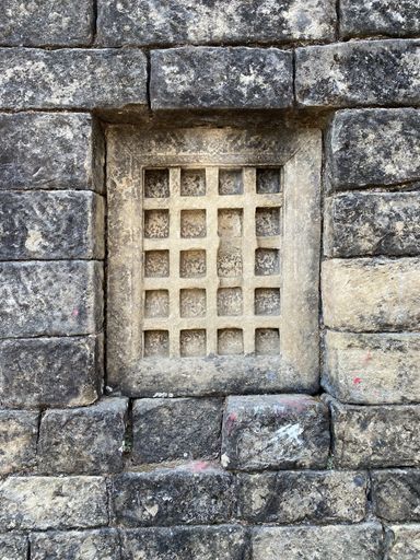 A vertical shot of an old wooden locked window on a stone wall