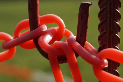 A closeup shot of red plastic barrier chains on rusted metal