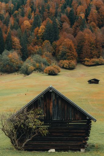A high-angle shot of a rustic wooden cabin in a vast open field with a tranquil atmosphere