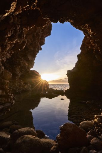 A vertical shot of a beautiful seascape through the rocks at sunset
