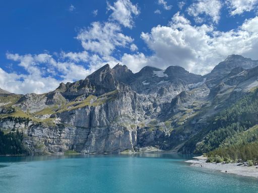 A landscape of a crystal-clear lake surrounded by rocky mountains in Switzerland