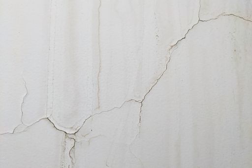 A closeup of a long crack in an old white discolored wall