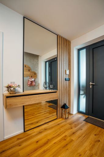 An interior wooden wardrobe door with a full-length reflective mirror in the hallway next to the entrance door