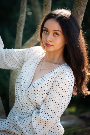 A beautiful young female in a sundress posing near trees in Majik Forest, Cape Town, South Africa