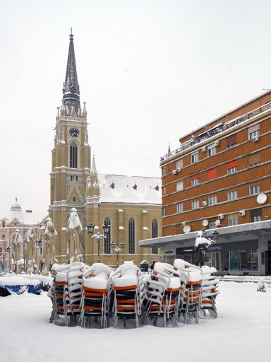 Novi Sad, Serbia, March 23, 2018: Winter day in the center, the church named after Mary and chairs covered with snow