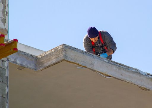 A male construction worker working on a narrow ledge