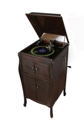 An antique vintage record player and a vinyl record album isolated on a white background.