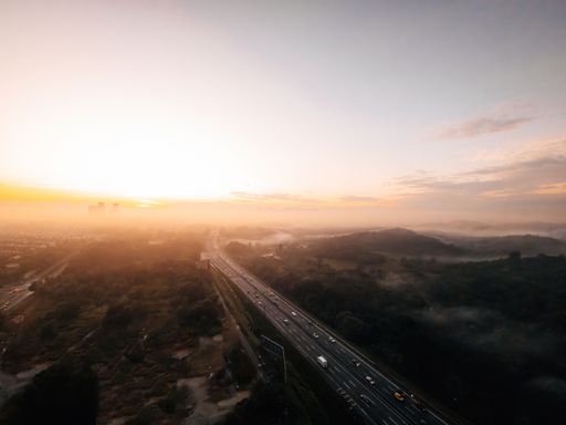An aerial view of a foggy highway cutting through a rainforest area in Malaysia