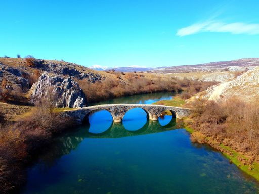 A bridge provides passage over a pristine river running through a lush valley