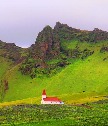 A vertical shot of the beautiful Reyniskirkja Church located on the hillside above Vik with a big cliff in the background