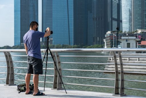 Chinese photographer taking photos at Marina Bay downtown Singapore on sunny day