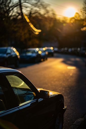 A scenic shot of a street with various vehicles driving down it as the sun sets in the background