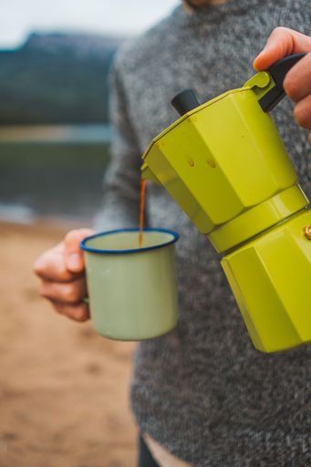 person serving coffee in a campsite in autumn