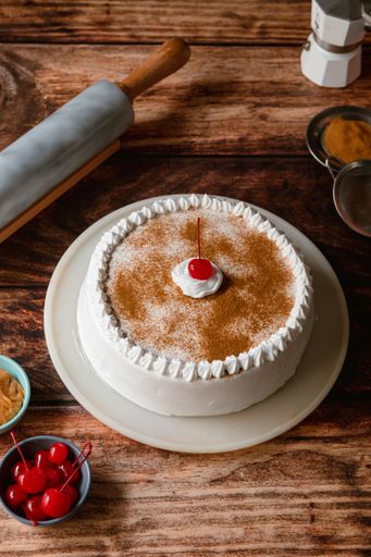 A delicious tres leches cake with ingredients on a wooden table