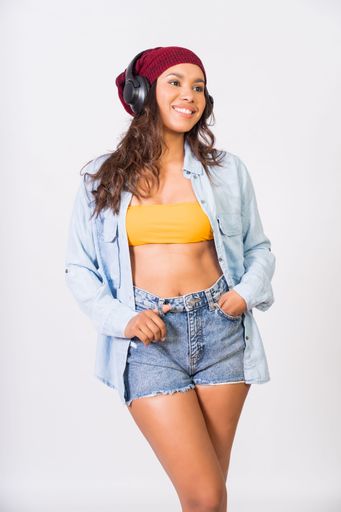 A smiling Latin woman wearing headphones and enjoying her favorite music