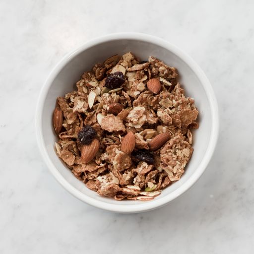 A top view of a bowl of healthy cereal with nuts and oats.