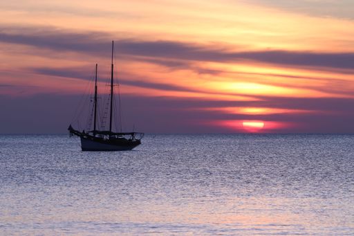 A sailing vessel is pictured against the stunning backdrop of a sunset near Koh Lanta, Thailand