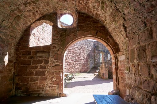 An old stone building with an arch looking to the terrace with benches