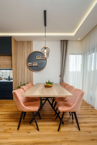 An interior shot of a modern dining room with a wooden table and pink armchairs