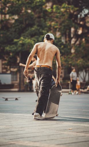 A shirtless young man in a skate park about to ride his skateboard